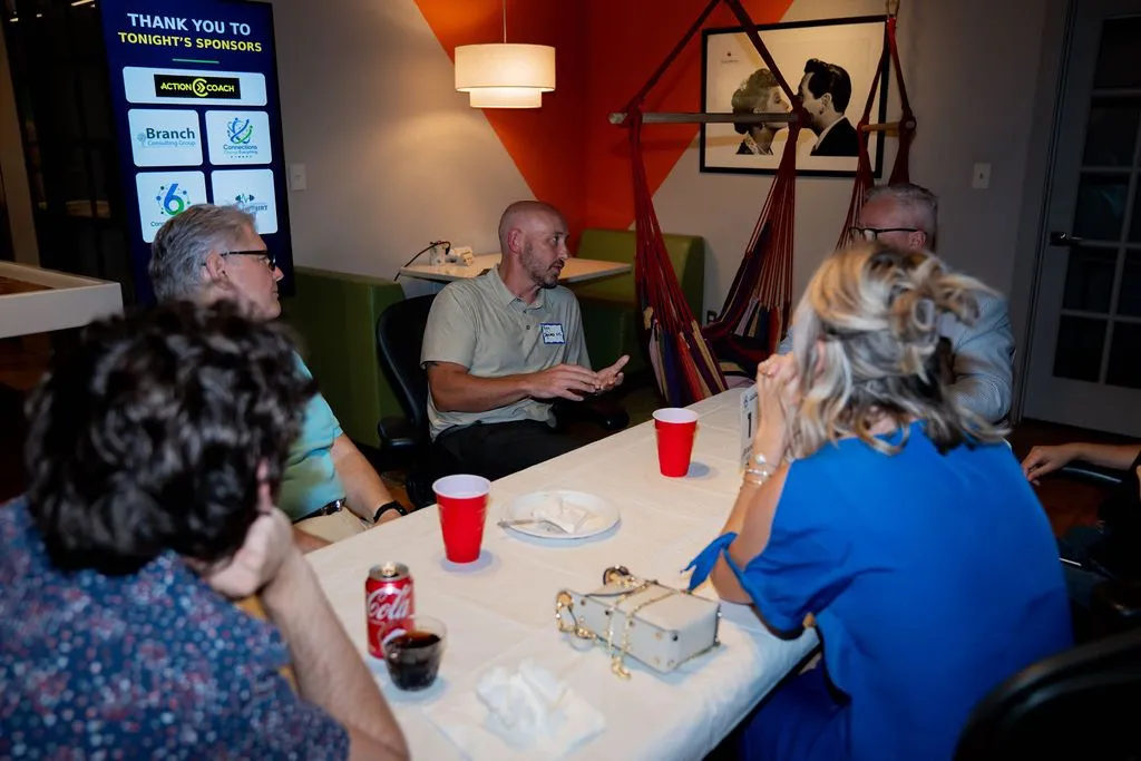 Attendees seated around a table with a sponsor banner behind them